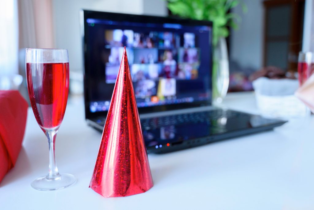 red wine, party hat and a virtual event on a laptop