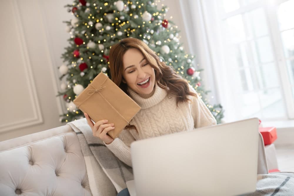 Happy woman opening a Christmas present on a video call