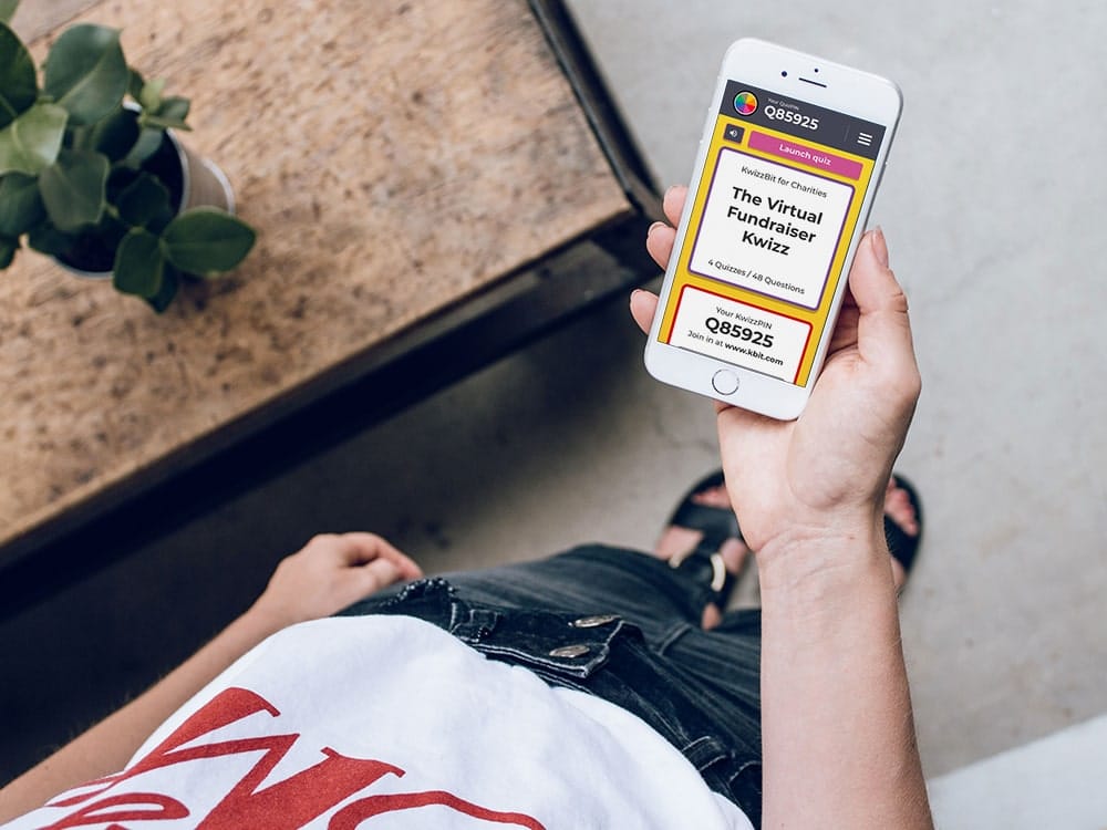 Person holding white iPhone with virtual charity quiz on screen